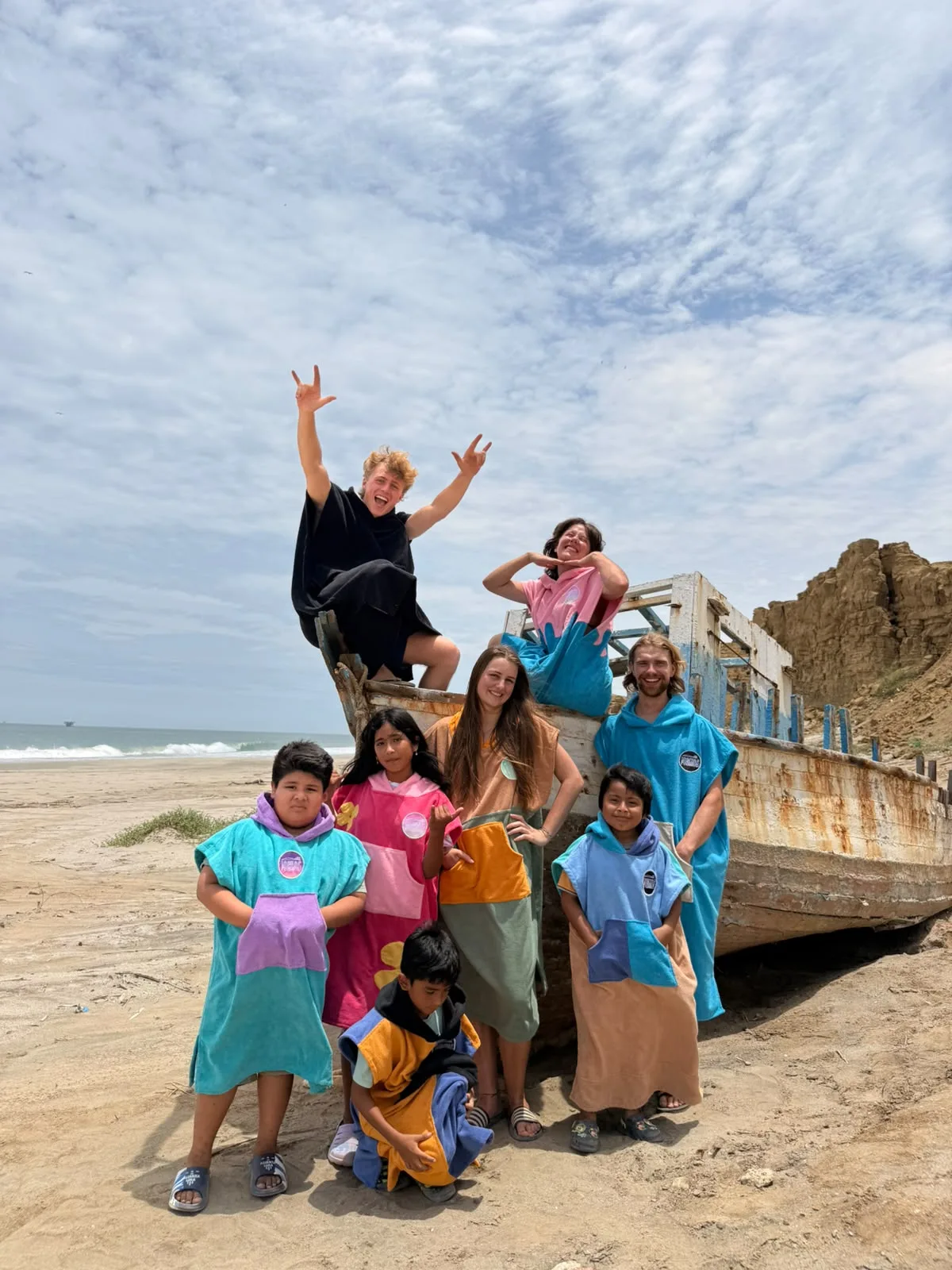 Local kids and visitors in ponchos on a fishing boat on the beach in Lobitos